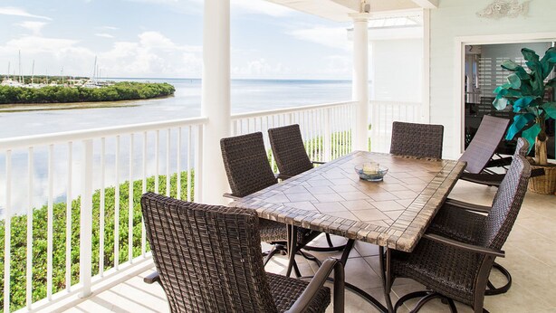 A covered outdoor dining area with a view of the sea and boats. -  Oceanfront Marina Condo With All Luxuries (Key West)