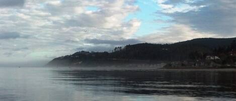 A calm body of water with a boat's edge and a cloudy sky.