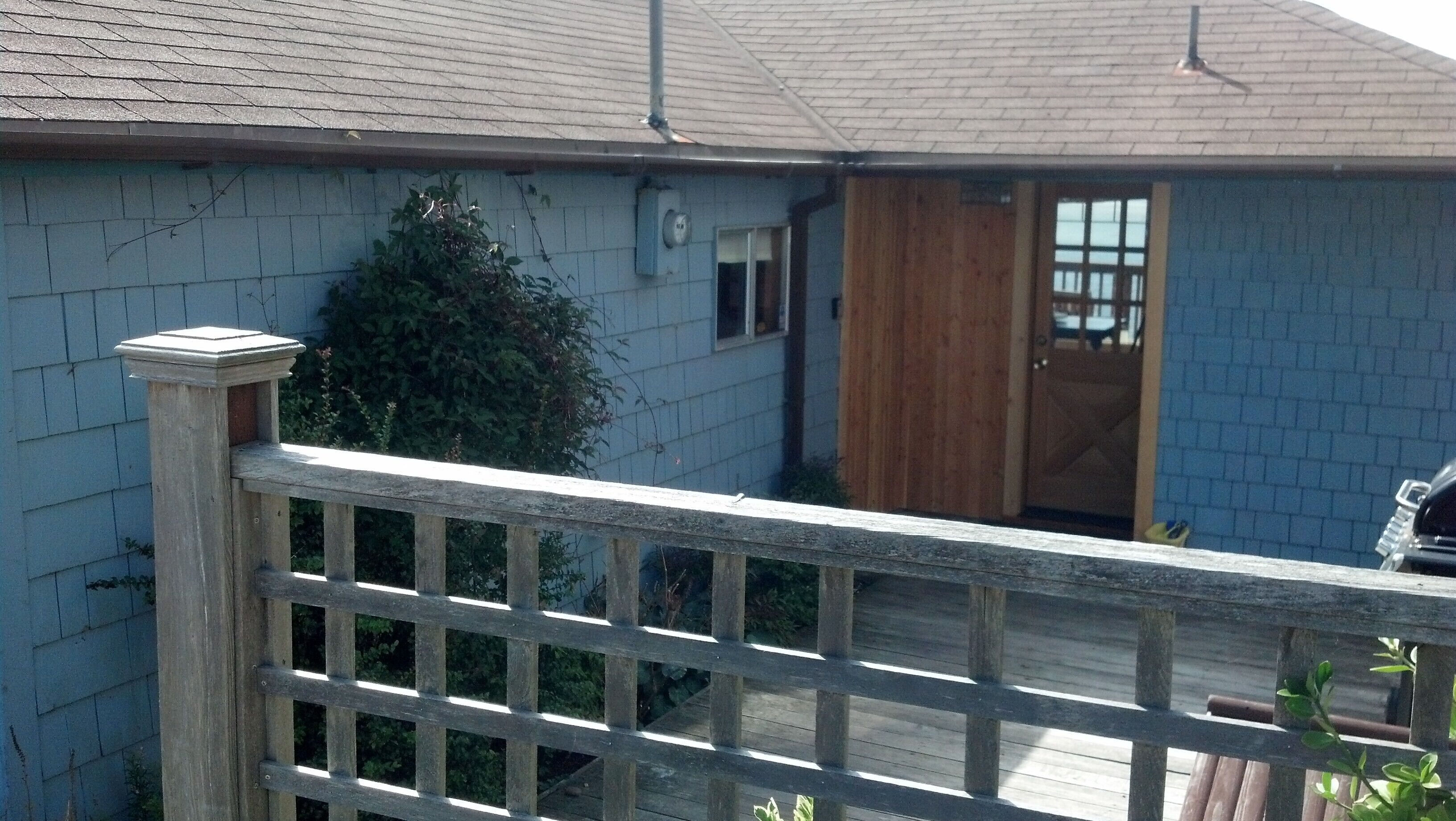 Una casa residencial con terraza de madera y puerta de acceso al interior.