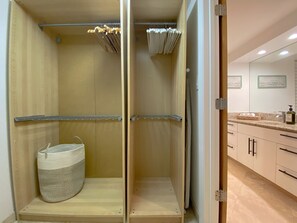 A walk-in closet with wooden shelving, a hanging rack, and a woven basket.