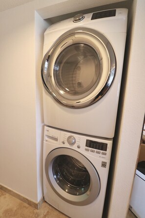 Een gestapelde wasmachine en droger met bedieningspanelen en een voorlader.