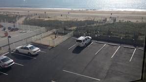 A parking lot with several cars, a white fence, and a view of the beach and ocean. - Direct Oceanfront 2 Bedrm, 2 Bath ATLANTIS Coastal Hwy at 103rd St (Ocean City)