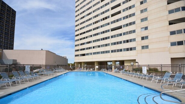 A rectangular swimming pool with a 'NO DIVING' sign, surrounded by lounge chairs and a tall building in the background. - Direct Oceanfront 2 Bedrm, 2 Bath ATLANTIS Coastal Hwy at 103rd St (Ocean City)