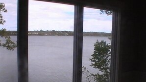 A view through a window of a large body of water, likely a lake, with trees and a distant shoreline visible.