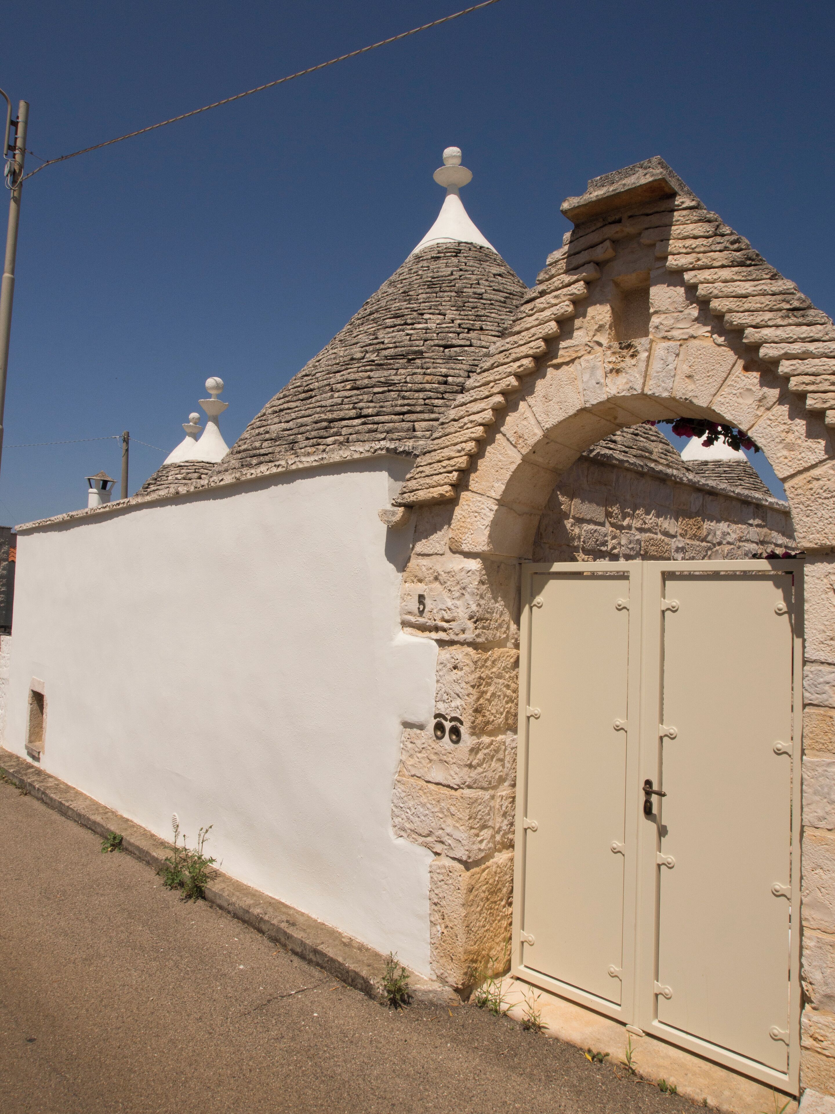 A building with a white facade, stone arches, and a beige door.