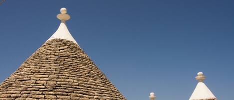 A row of traditional stone-roofed buildings with white-topped conical roofs.