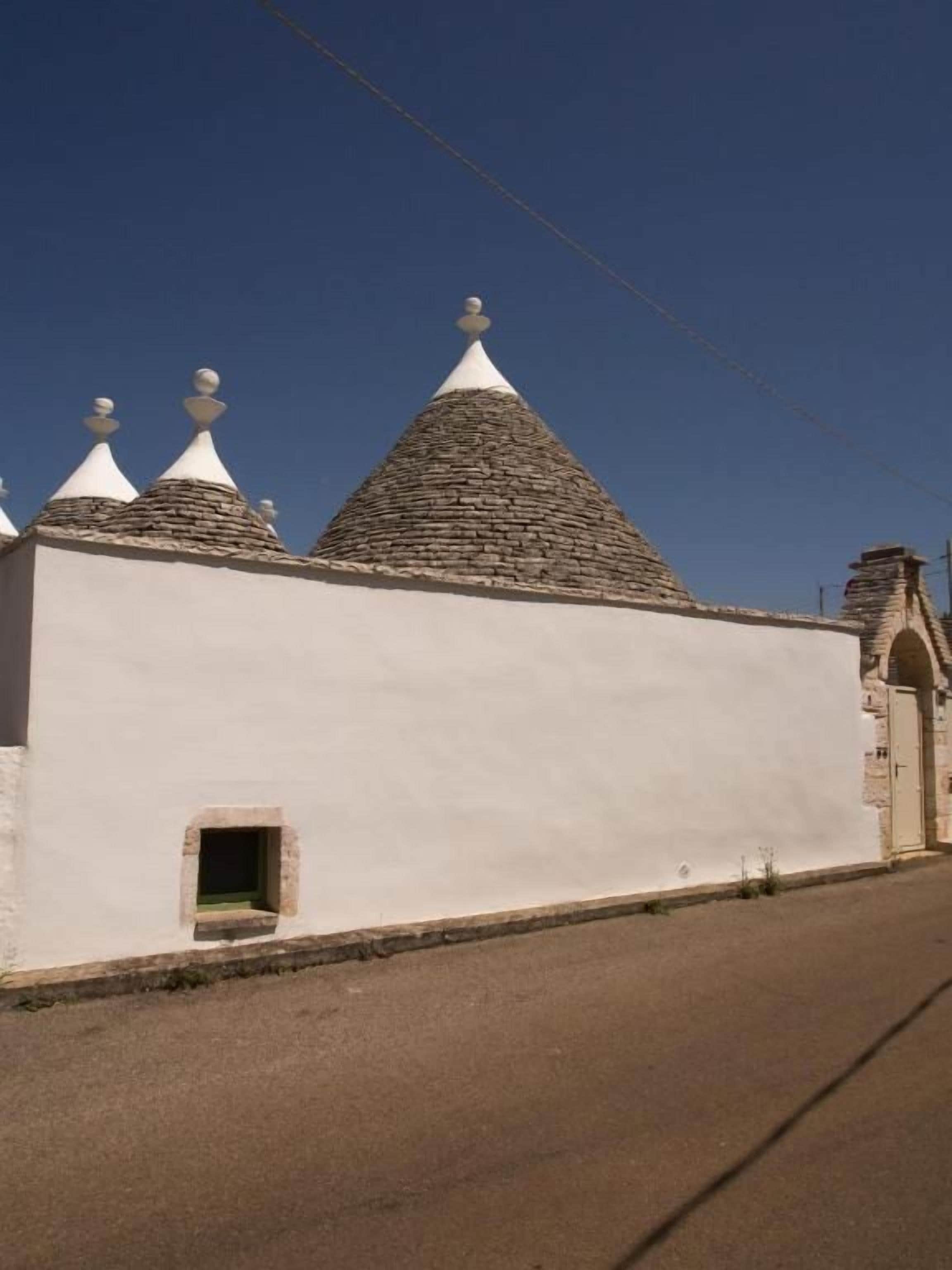 A building with a white facade, a small window, and a unique conical roof structure.