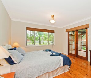 Un dormitorio con cama, cómoda, ventana y puerta que da a un balcón.