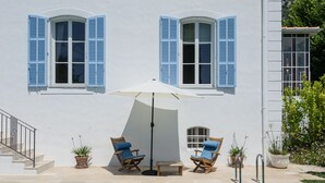 Un espace aménagé au bord de la piscine, comprenant deux chaises longues, une table et un parasol.