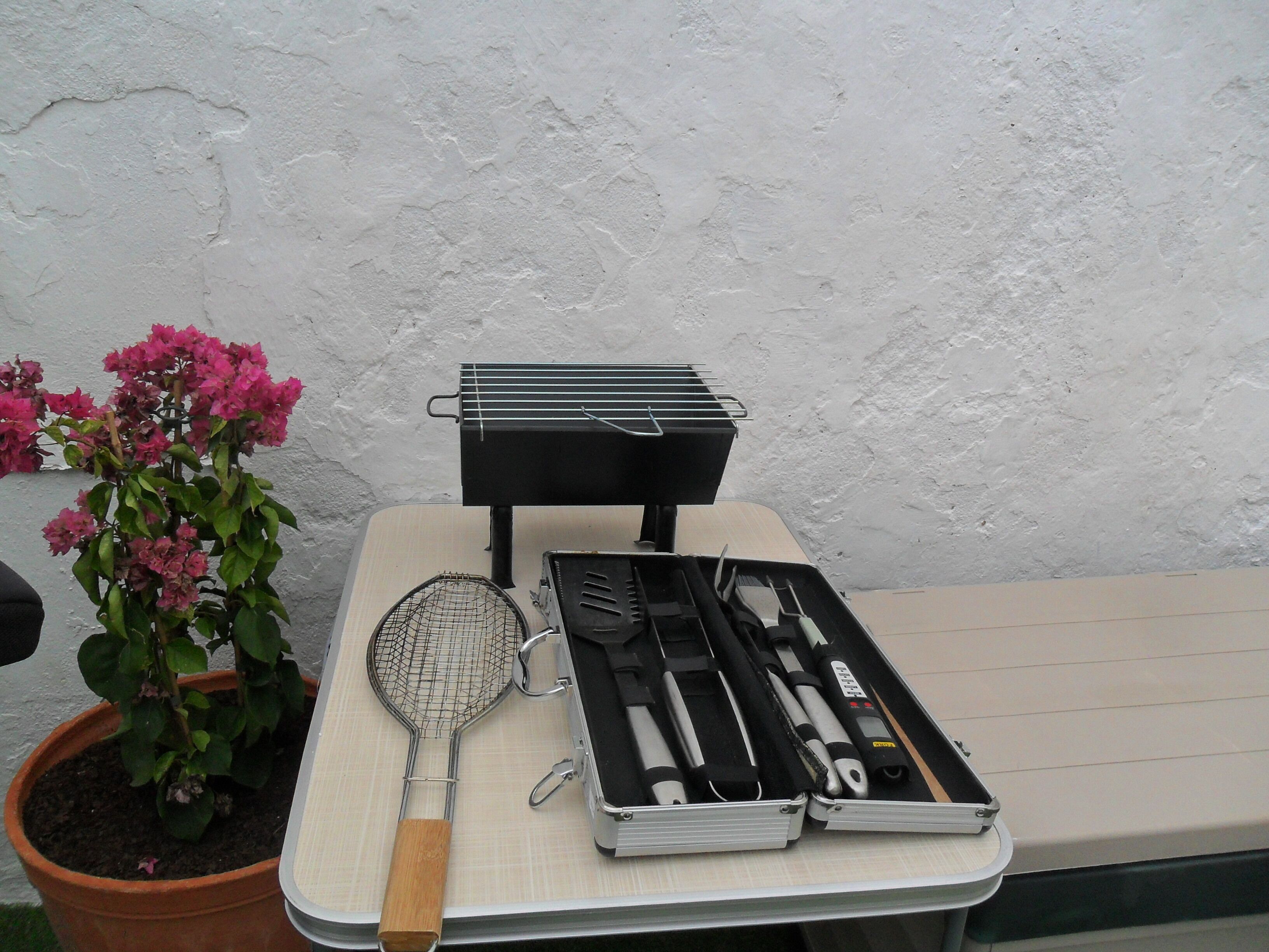 A table with a grill, a tennis racket, and a set of golf clubs.