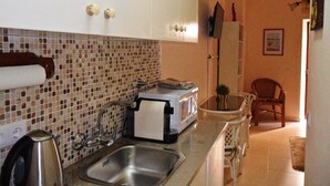 A kitchen with a tiled backsplash, stainless steel sink, and white cabinets.