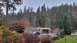 A modern building with a parking area, surrounded by a forested landscape.