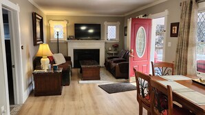 A living room with a fireplace, a television, and a dining area with a table and chairs.