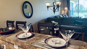 Un coin repas avec une table dressée pour deux personnes, agrémenté d’un bol décoratif, d’un verre à martini et d’une assiette ornée d’un motif représentant un bonhomme de neige.