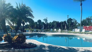 Une piscine d’un bleu éclatant, avec des chaises longues et des palmiers.