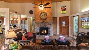 Un amplio salón con chimenea, muebles de cuero y televisor.