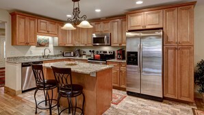 A modern kitchen with wooden cabinets, stainless steel appliances, and a central island with bar stools.