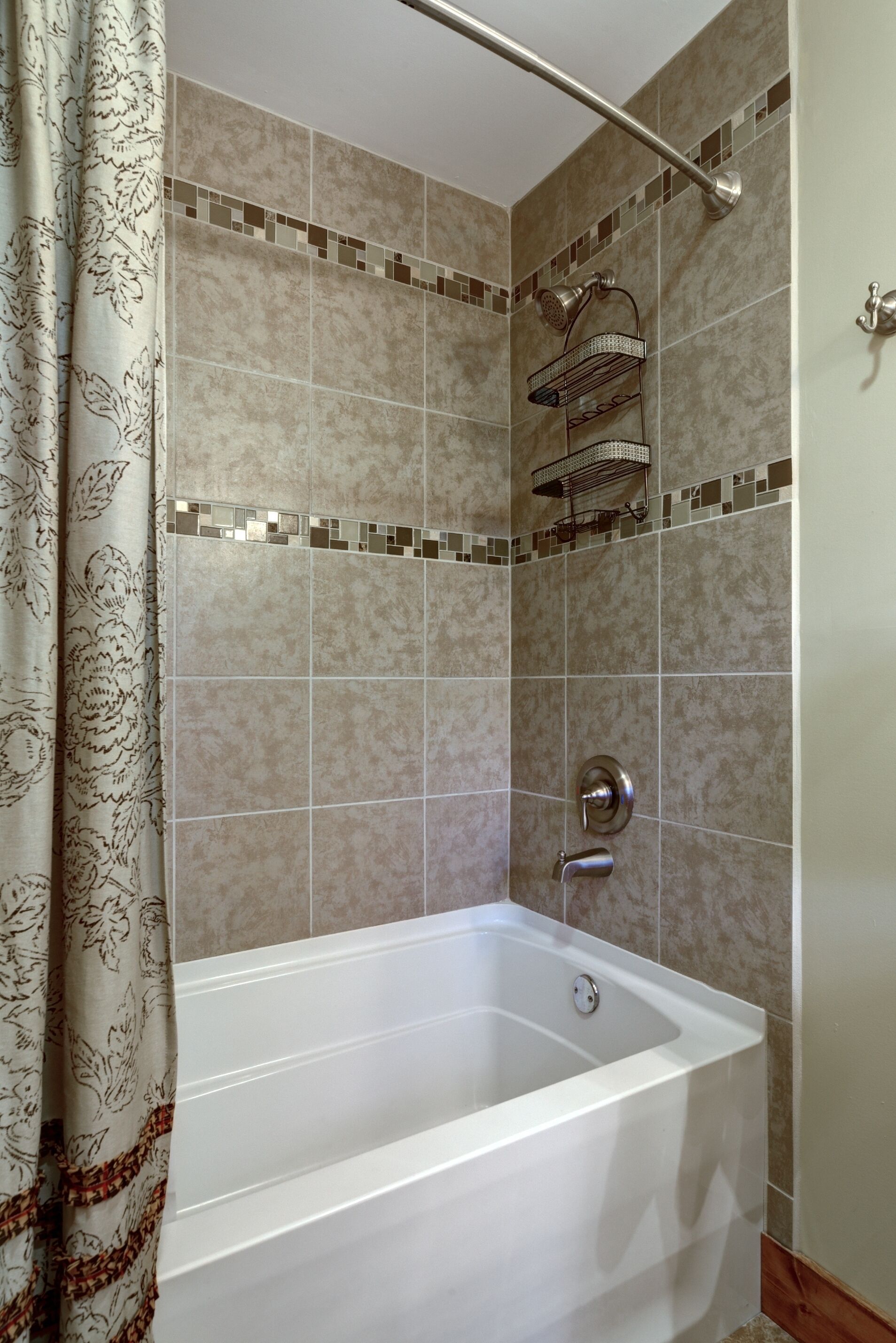 A modern bathroom with a bathtub, shower, and tiled walls.