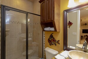 A bathroom with a glass shower enclosure, a toilet, a sink with a large mirror, and a decorative fish wall art piece. - South Padre Island Spacious!!! 3 Bedroom 2 Bath #2015-837252 (South Padre Island)