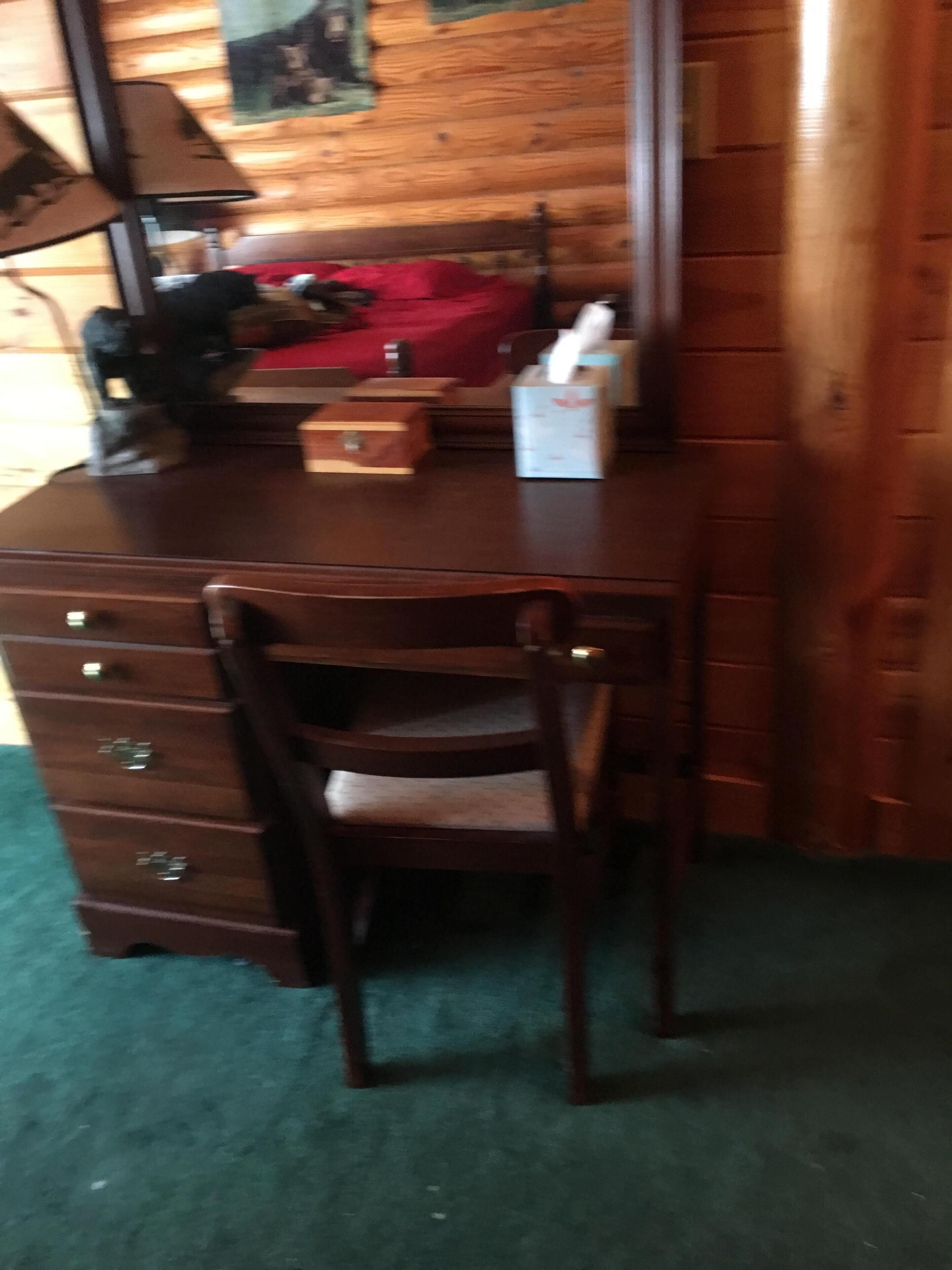 A wooden desk with drawers and a chair.