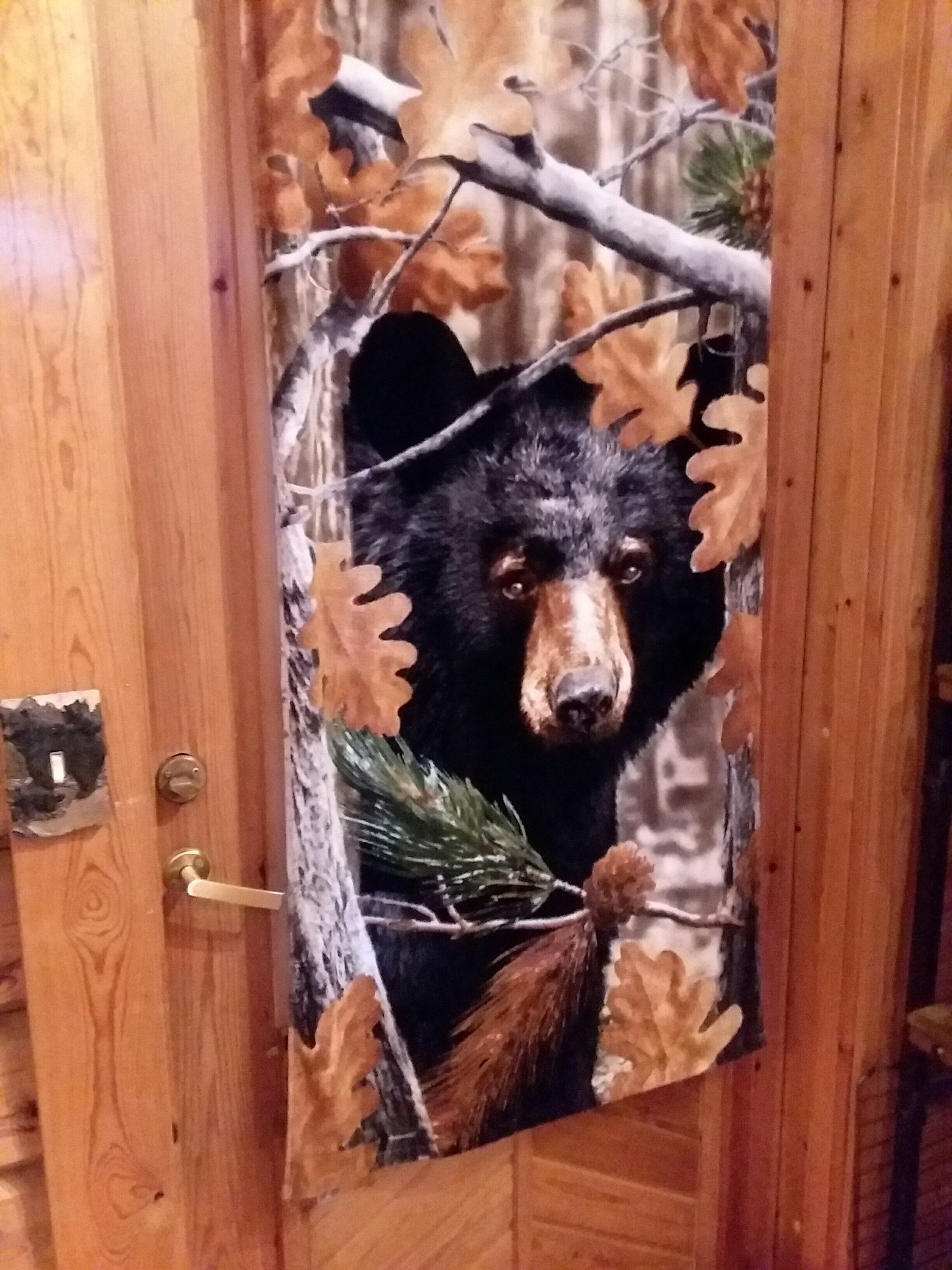 A wooden door with a bear head decoration peeking through a hole in the door.