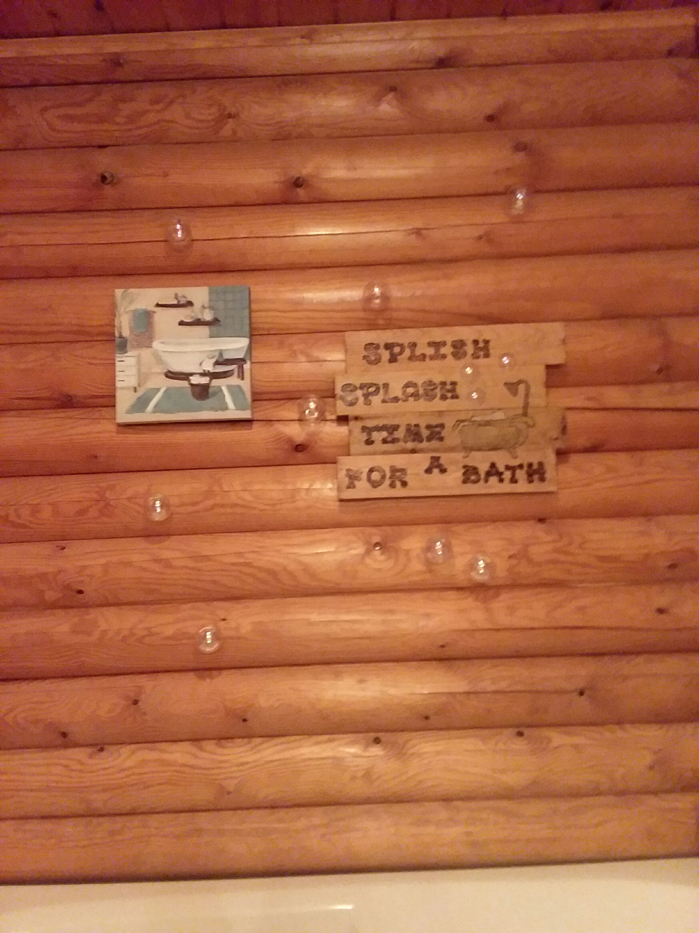 A wooden wall with a sign that reads "SPLASH FOR A BATH" and a small picture of a bathroom.