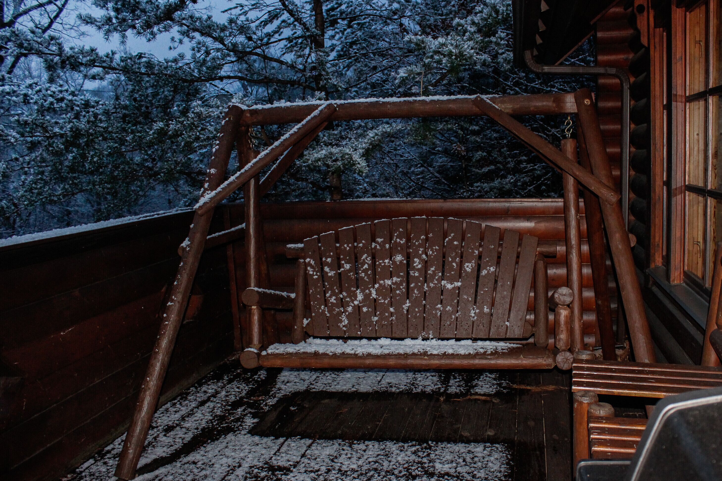 A wooden staircase leading to a cabin with a metal railing and a bench.