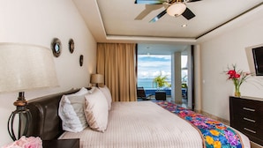 A hotel room with a bed, a ceiling fan, a nightstand with a lamp, a dresser, and a view of the outdoors. - Best location right on los muertos beach, Sky Suite E (Amapas)