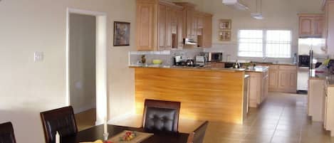 A spacious kitchen with wooden cabinets, a central island, and a dining area with a table set for four.
