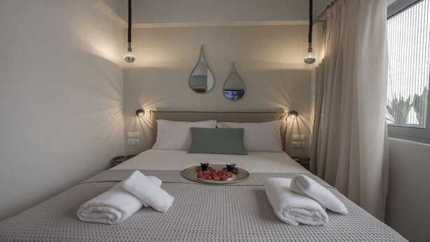 A neatly made bed with two towels, a tray with strawberries, and two wall-mounted mirrors. - Ermou Stylish Suite Studio (Athina)