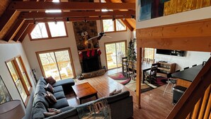 Amplia sala de estar con un sofá modular grande, una chimenea y un comedor con mesa y sillas de madera.