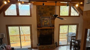 Amplia sala de estar con chimenea, ventanas grandes y una terraza de madera.
