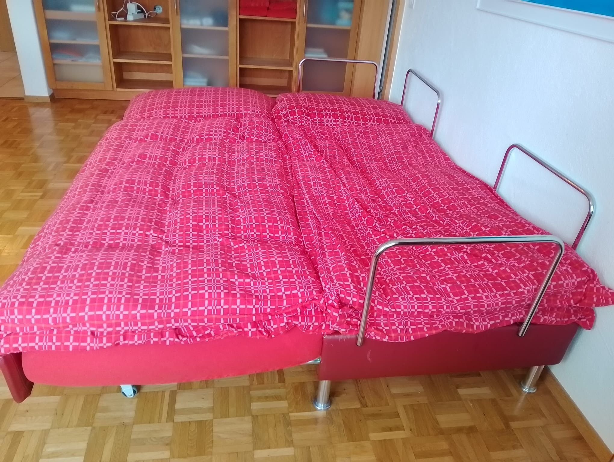 Een kamer met twee eenpersoonsbedden, een houten vloer en een houten kast met glazen deuren.