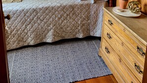 Een houten slaapkamer met een bed, een dressoir en een raam.