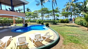 A pool area with lounge chairs and a covered seating area.