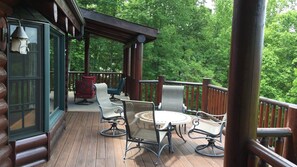 A wooden deck with wicker furniture and a glass door.