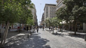 A cobblestone street lined with trees and buildings, featuring pedestrians and outdoor seating areas. - Ermou Stylish viewing studio (Athina)