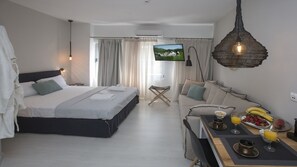 A modern hotel room with a bed, a sofa, a dining area with breakfast items, and a TV on the wall. - Ermou Stylish viewing studio (Athina)