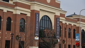 A brick building with large arched windows and a sign that reads "Hershey Story".