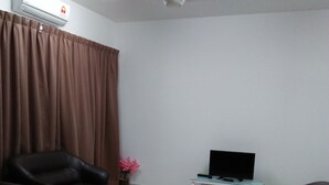 A living room with two black sofas, a TV on a stand, a ceiling fan, and a window with brown curtains.