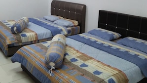 A room with two beds, each with patterned bedding and pillows, a brown headboard, and a white air conditioning unit on the wall.