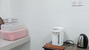 A small kitchenette with a coffee maker, kettle, and storage container.
