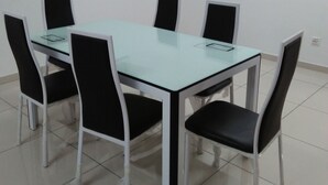 A conference room with a glass table and black chairs, a painting on the wall, and a tiled floor.