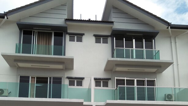 A modern multi-story building with balconies, large windows, and a gated entrance.
