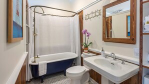 A bathroom with a bathtub, toilet, sink, and shower curtain. - Studio Blu - Historic Key West Studio + Bikes (Key West)