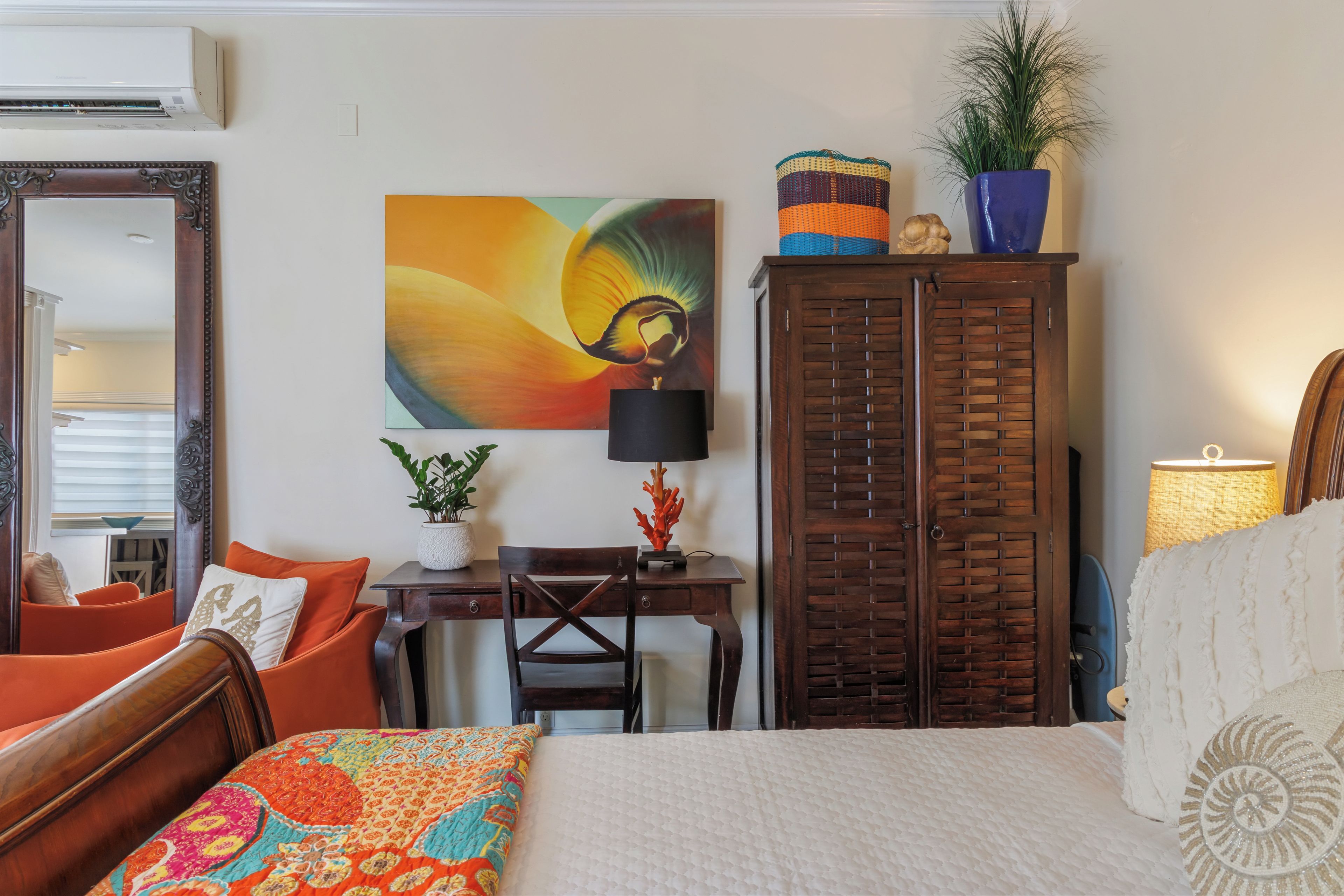 Une chambre d’hôtel avec un lit, un bureau, une chaise, une armoire et un tableau au mur.