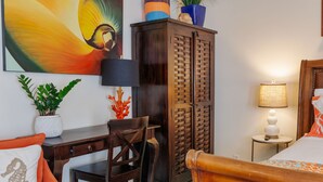 A bedroom with a wooden bed, a desk, a chair, a wardrobe, and a nightstand with a lamp. - Studio Blu - Historic Key West Studio + Bikes (Key West)