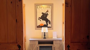 A wooden barn-style room with a mounted poster, a lamp, and a fireplace.