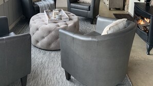 A cozy living room with grey upholstered furniture, a fireplace, and a stone wall.