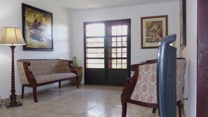 Una habitación con un sofá, una silla, una lámpara y dos cuadros.
